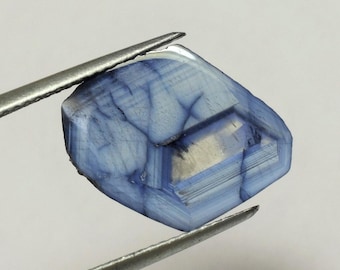 Tranche de saphir pseudo hexagonal bleu ciel avec foudre bleu foncé, ce corindon chatoyant à 6 côtés mesure 17x14 mm et pèse 6.83 carats