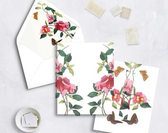 May include: White stationery set featuring watercolor illustrations of pink roses, green leaves, and butterflies. Includes an envelope, blank cards, and stamps. The floral design is repeated on the envelope interior and card borders.