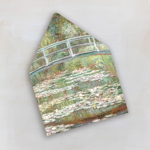 May include: An envelope featuring a painting of a bridge over a pond filled with lily pads. The artwork uses a palette of greens, whites, and browns, with a white railing on the bridge. The style is reminiscent of impressionist art.