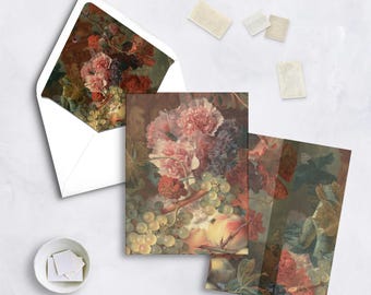 May include: Stationery set featuring a floral still life design. The set includes greeting cards, an envelope, and stamps. The artwork showcases pink, purple, and red flowers, green grapes, and peaches.