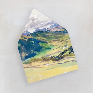 May include: A watercolor painting of a landscape with green hills, blue trees, and a yellow sky. The painting is on a white envelope.
