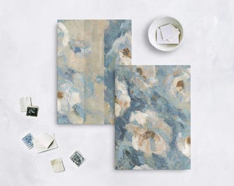 May include: Two abstract art prints with a floral design in shades of blue, white, and beige. A small white bowl with square stickers and several vintage stamps are also visible.