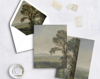 May include: A set of landscape art greeting cards and envelopes. The cards feature a painting of a large tree in a field with a mountain range in the background. The envelopes are white and the stamps are beige.