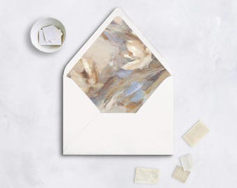 May include: A white envelope with a painted interior in shades of beige, brown, and blue. Several postage stamps and a small white bowl with stamps are also present, all on a white surface. The envelope is open, revealing the artwork.