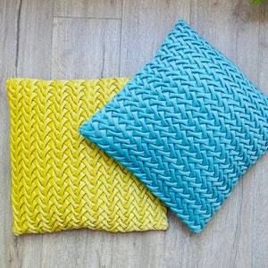 May include: Two decorative throw pillows with a woven pattern. One pillow is yellow and the other is blue.