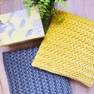 May include: Two decorative throw pillows with a woven pattern. One pillow is a dark gray color and the other is a bright yellow color.