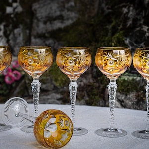 Puede incluir: Juego de seis copas de vino de cristal &aacute;mbar con intrincados dise&ntilde;os tallados. Las copas tienen una copa redonda y un tallo largo y delgado.