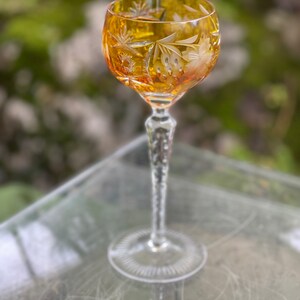 Puede incluir: Un vaso alto y transparente con un dise&ntilde;o de cristal tallado. El vaso tiene una copa redonda y un tallo largo y delgado. La copa es de color &aacute;mbar.