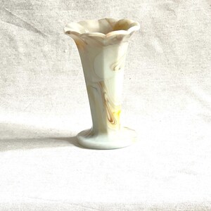 May include: A white and brown marbled glass vase with a scalloped rim and a flared base.