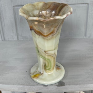 May include: A white, brown, and green swirled glass vase with a scalloped top and a flared base.