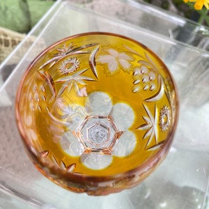 Puede incluir: Un cuenco de vidrio transparente con un tono amarillo &aacute;mbar y dise&ntilde;os intrincados de vidrio cortado. El cuenco tiene un patr&oacute;n de estrella y un dise&ntilde;o floral.