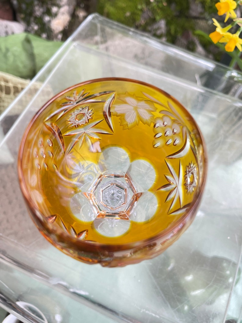 Puede incluir: Un cuenco de vidrio transparente con un tono amarillo &aacute;mbar y dise&ntilde;os intrincados de vidrio cortado. El cuenco tiene un patr&oacute;n de estrella y un dise&ntilde;o floral.