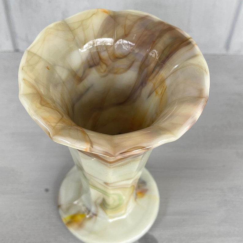 May include: A white and brown marbled glass vase with a flared top and a round base. The vase has a geometric pattern and is made of a translucent material.