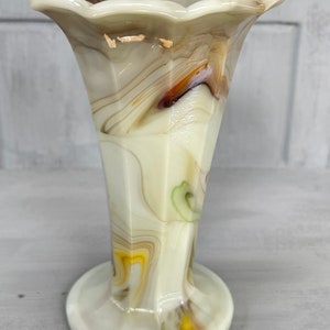 May include: A white, brown, and yellow swirl glass vase with a scalloped top and a flared base.