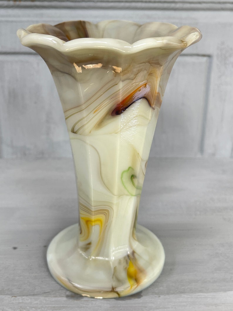May include: A white, brown, and yellow swirl glass vase with a scalloped top and a flared base.