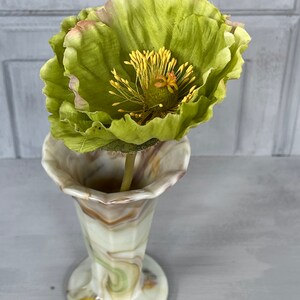 May include: A green silk poppy flower in a swirled glass vase with brown, white, and green patterns.