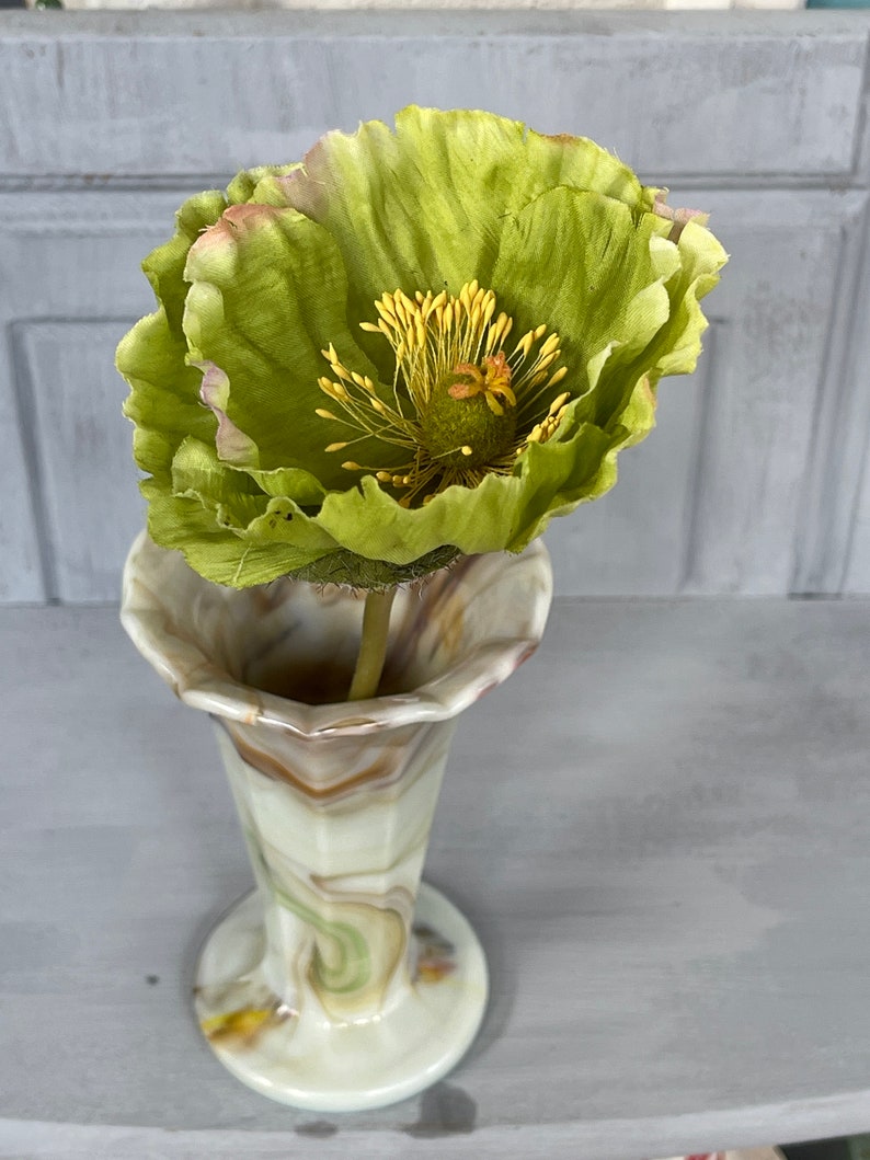 May include: A green silk poppy flower in a swirled glass vase with brown, white, and green patterns.