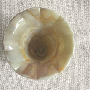 May include: A white and brown swirl glass vase with a fluted rim.