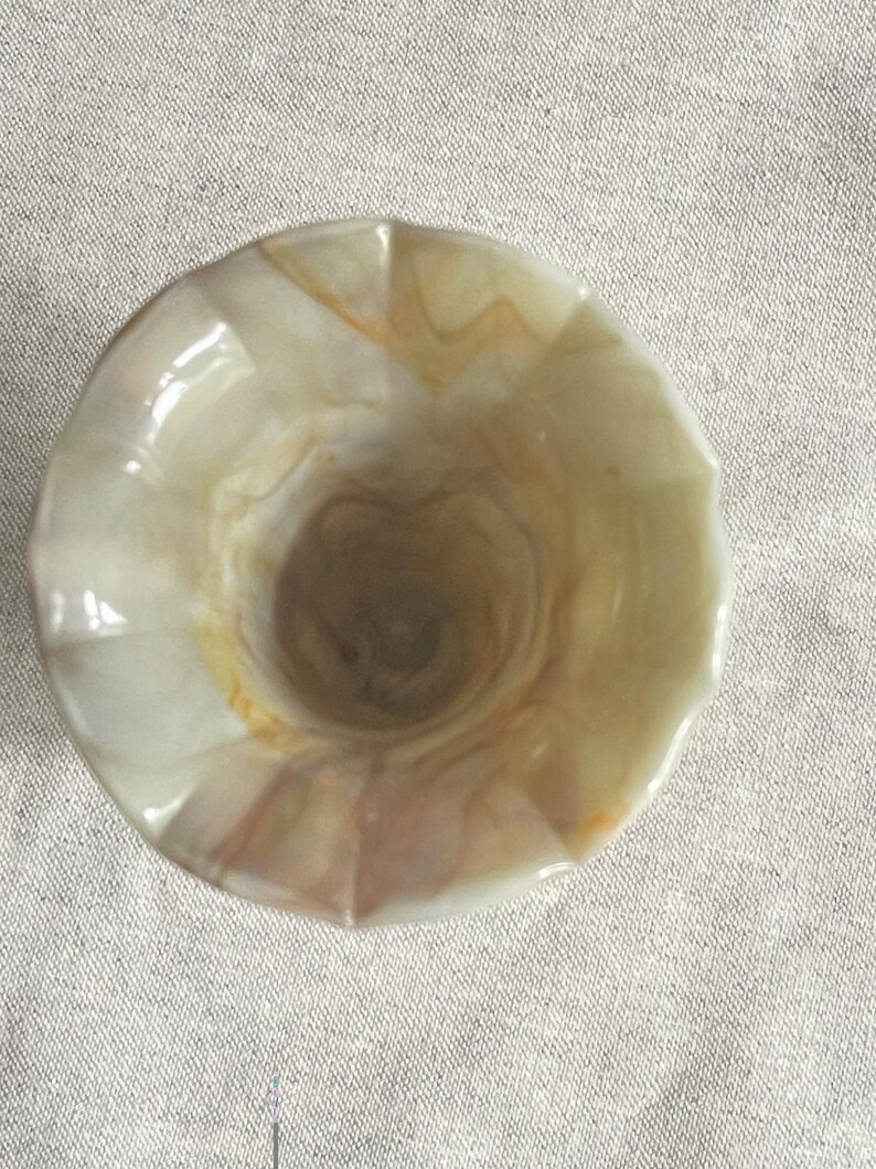 May include: A white and brown swirl glass vase with a fluted rim.