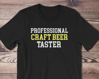 Puede incluir: Camiseta negra con texto blanco que dice "Professional Craft Beer Taster" en una caja amarilla.