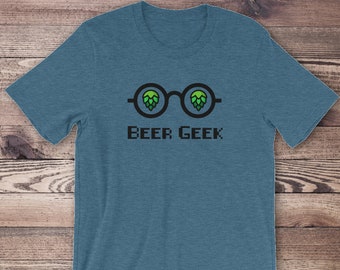 Puede incluir: Una camiseta azul con un gráfico de unas gafas con lúpulos para lentes y el texto "BEER GEEK" debajo.