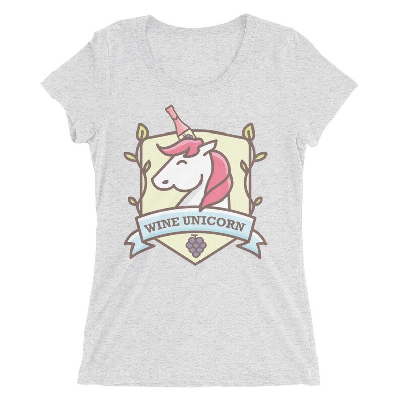 Puede incluir: Una camiseta gris claro con un gr&aacute;fico de un unicornio con una botella de vino en la cabeza. El gr&aacute;fico est&aacute; dentro de un escudo con vides y un racimo de uvas. El texto "Wine Unicorn" est&aacute; en una pancarta azul.