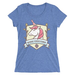 Puede incluir: Una camiseta azul con un gr&aacute;fico de un unicornio con una botella de vino en la cabeza. El gr&aacute;fico est&aacute; dentro de un escudo con vides y el texto "Wine Unicorn".