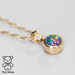 Op de afbeelding: Een gouden ketting met een klein rond hanger met een kleurrijke opaal edelsteen.