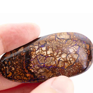 May include: A brown and purple opal with a unique, intricate pattern of veins and swirls. The opal is a natural gemstone with a smooth, polished surface.