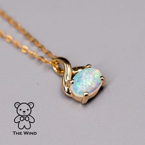 May include: A gold chain necklace with a pendant featuring a white opal gemstone set in a gold swirl design.