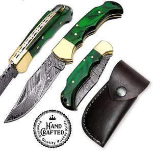 May include: A collection of handcrafted pocket knives with green handles and Damascus steel blades. The knives have brass accents and are displayed with a brown leather sheath. The image includes a circular logo that reads "Hand Crafted Quality Pocket Knife."