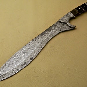 May include: A silver-colored sword with a black and brown handle. The blade is decorated with a swirling pattern.