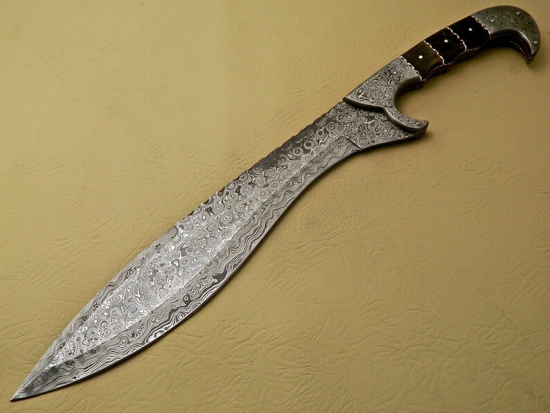 May include: A silver-colored sword with a black and brown handle. The blade is decorated with a swirling pattern.