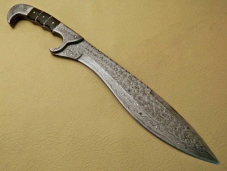 May include: A silver sword with a patterned blade and a black handle. The sword has a curved blade and a pointed tip.