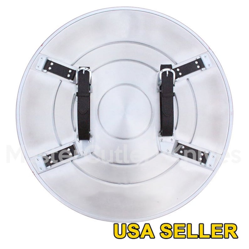 May include: A silver metal shield with a red, white and blue star design. The shield has black straps on the back for carrying.