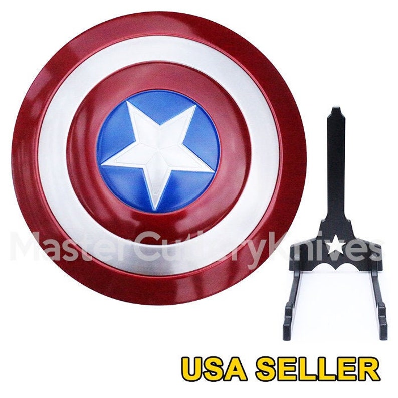 May include: A red, white and blue Captain America shield with a silver star in the centre. The shield is on a black stand with a star on it. USA SELLER is written in yellow letters at the bottom of the image.