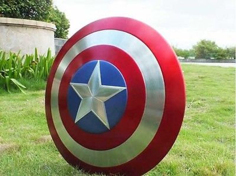 May include: A red, white and blue Captain America shield with a silver star in the centre. The shield is made of metal and has a glossy finish.