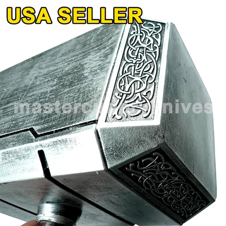 Pu&ograve; includere: Una replica argentata del martello di Thor, Mjolnir, con dettagli intricati e una superficie testurizzata. Il martello ha un manico nero e una testa argentata con un disegno di linee intrecciate.