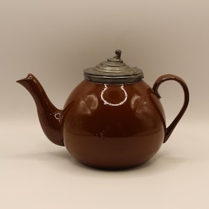 May include: A brown, round teapot with a curved spout and handle. The teapot has a silver-coloured lid and a glossy finish. The teapot is a classic design, suitable for serving tea.