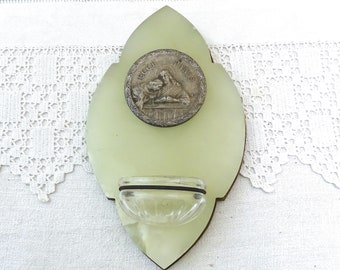 May include: A pale green ceramic wall-mounted inkwell with a decorative glass inkwell and a silver-toned religious medallion with the words "Regina Pacis" on it.