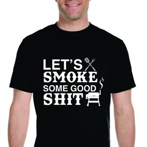 May include: A black t-shirt with white text that reads "Let's Smoke Some Good Shit" with a grill and grilling utensils graphic.