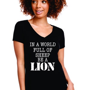 May include: Black v-neck t-shirt with white text that reads "In a world full of sheep be a lion".