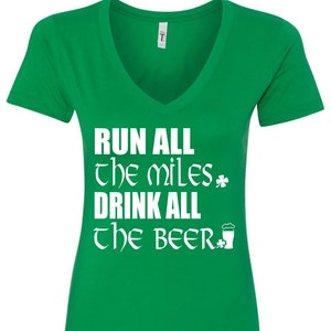Może przedstawiać: Zielona koszulka z dekoltem w kształcie litery V z białym napisem "Run all the miles, drink all the beer" z koniczyną i grafiką kufla piwa.