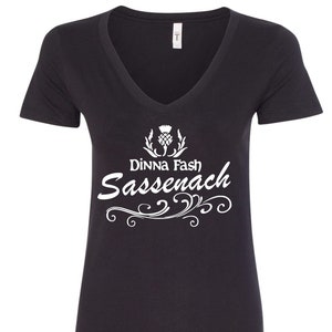 May include: Black V-neck t-shirt with a white graphic design featuring a stylized thistle and the text "Dinna Fash Sassenach".