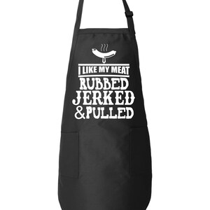 May include: Black apron with a white pocket and the text "I like my meat rubbed, jerked & pulled" with a white cartoon hot dog above the text.