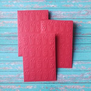 May include: Four red cards with a repeating pattern of coffee cups with steam coming from the top. The cards are stacked on top of each other.
