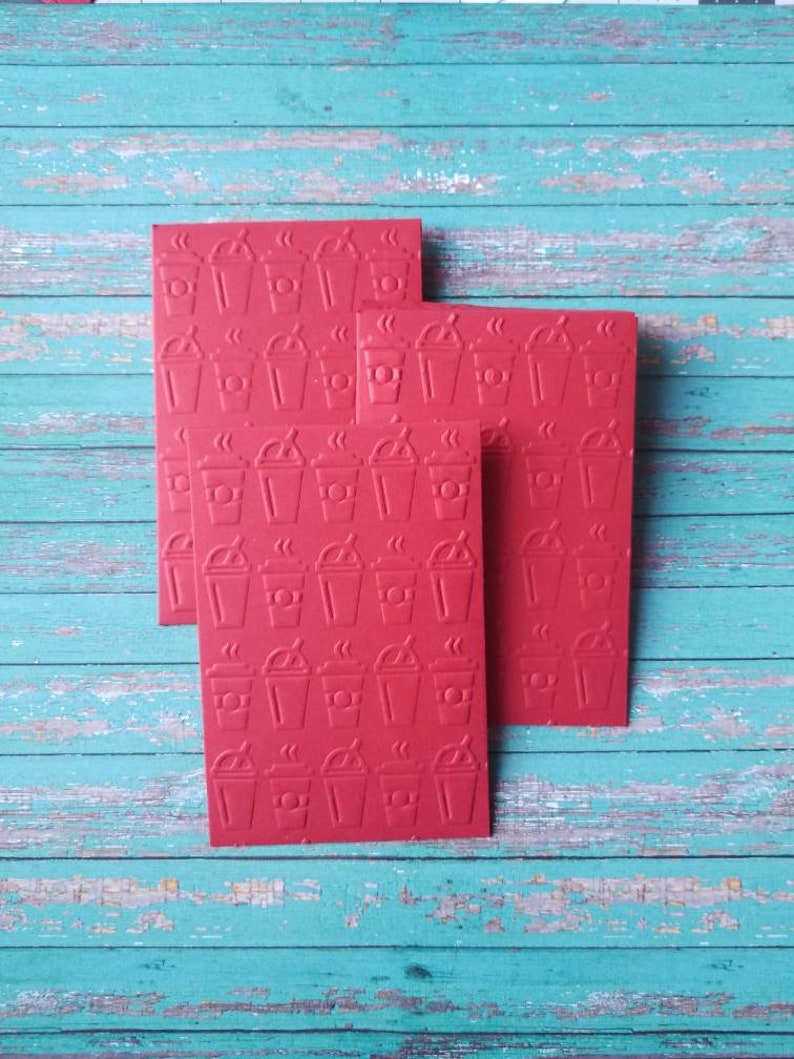 May include: Four red cards with a repeating pattern of coffee cups with steam coming from the top. The cards are stacked on top of each other.