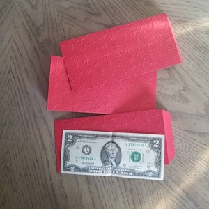 May include: Two red envelopes with a star pattern and a two dollar bill with a portrait of Thomas Jefferson.
