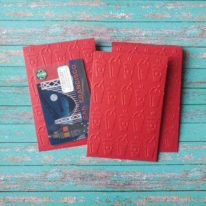 May include: Three red gift cards with a coffee cup pattern. The top card has a Starbucks gift card with a picture of the Golden Gate Bridge and the text "San Francisco".