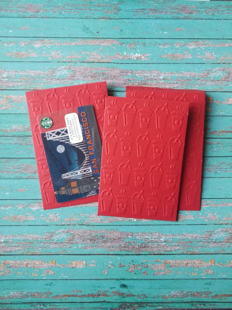 May include: Three red gift cards with a coffee cup pattern. The top card has a Starbucks gift card with a picture of the Golden Gate Bridge and the text "San Francisco".